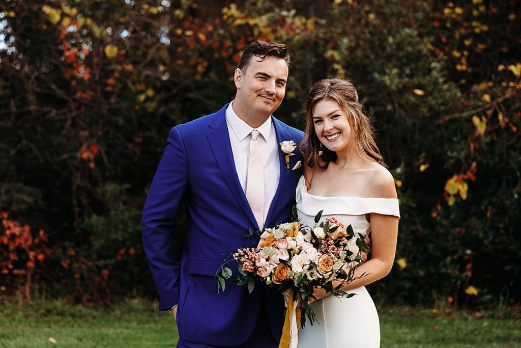 bride and groom hugging with fall wedding flowers