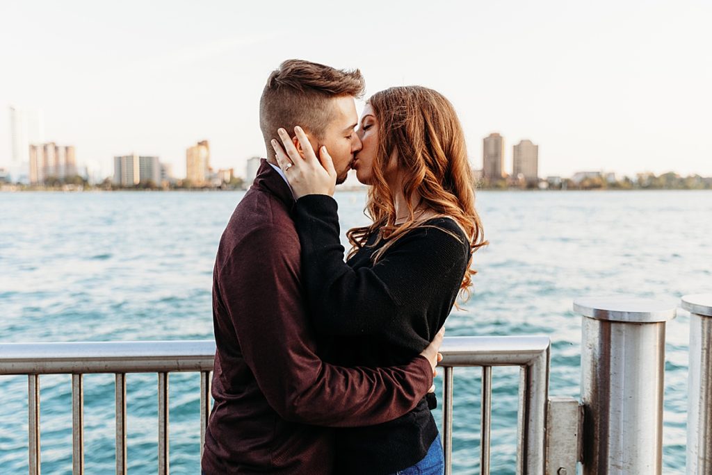 couple kissing eachother in front of the water in detroit