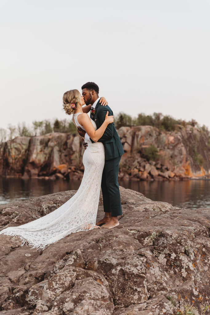 couple standing on rocks at elopement kissing