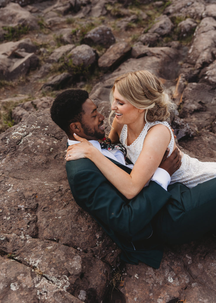 couple laying on rocks at beach elopement