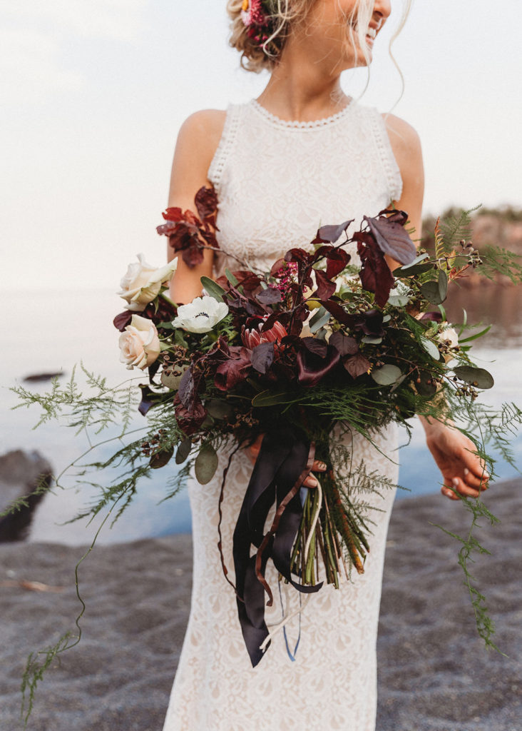 bride holding fall flowers at beach elopement