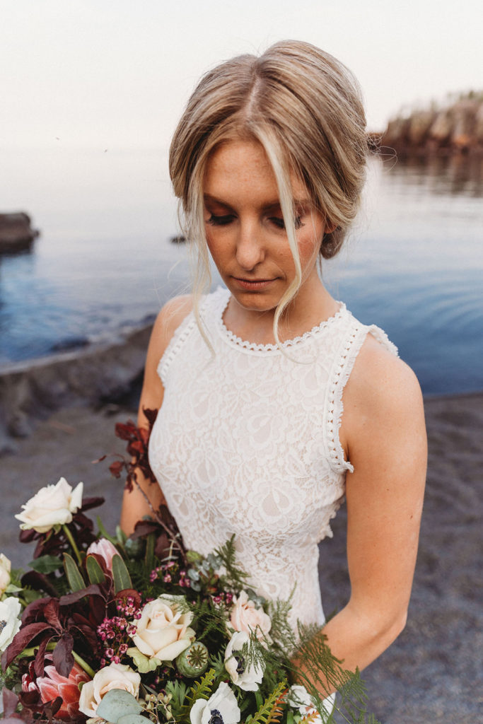 bride holding fall flowers at beach elopement
