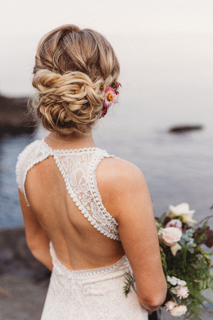 bride holding flowers with open back lace wedding dress