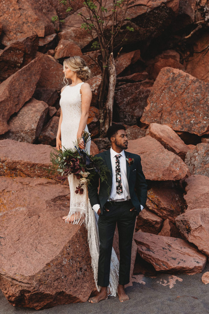 couple standing on rocks at beach elopement