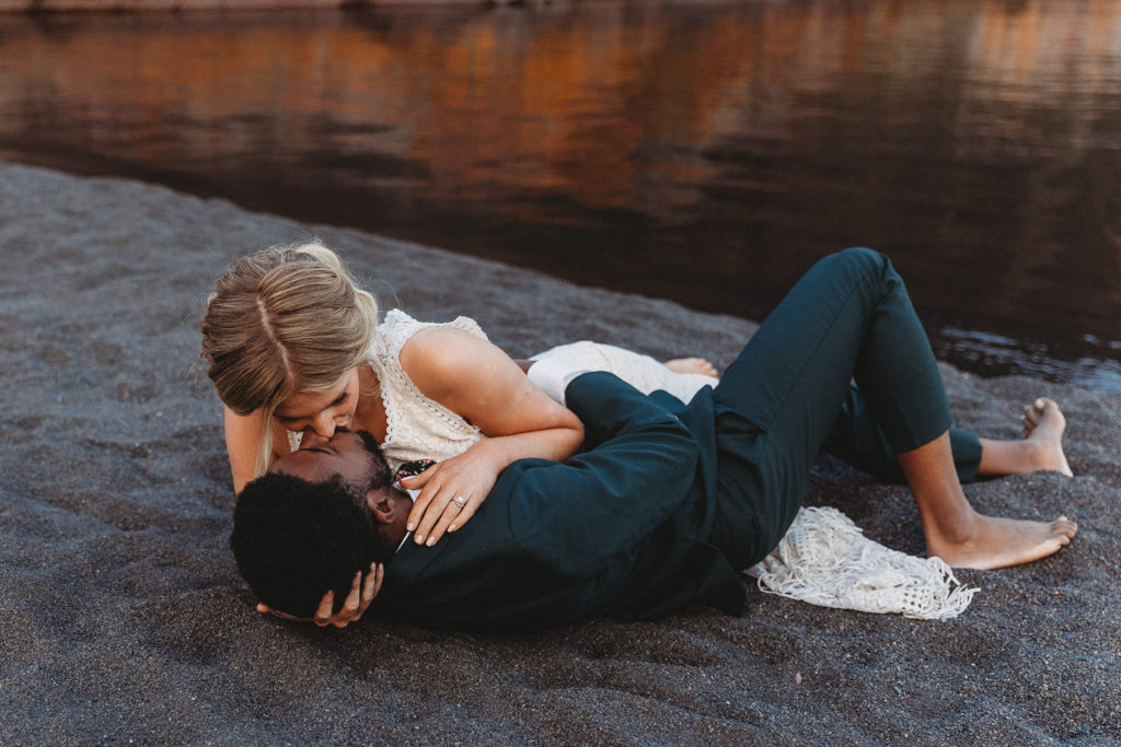 couple rolling around in sand during adventure elopement