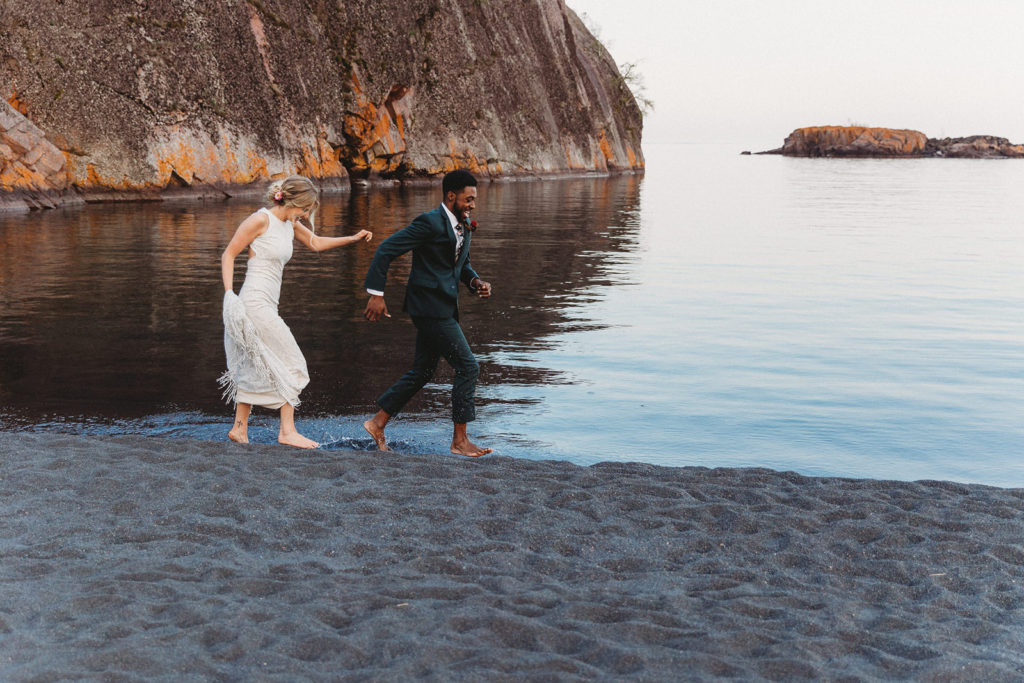 bride and groom running on beach at elopement in minnesota