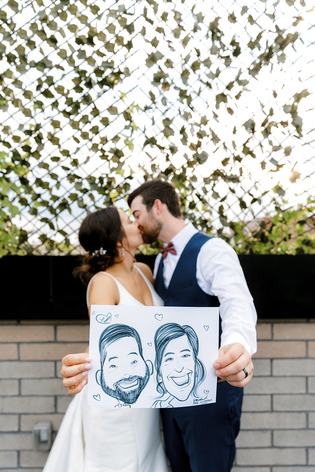 bride and groom kissing with a caricature with Michigan wedding photographer