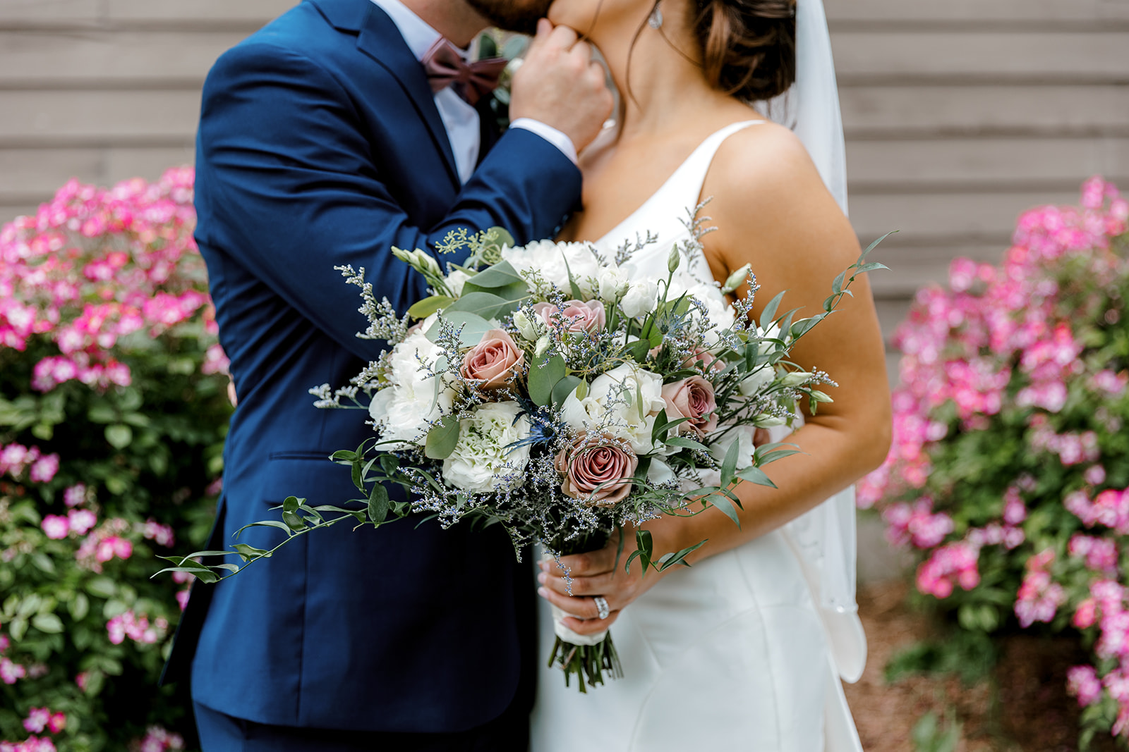 an upclose photo of bride and groom holding her wedding bouquet and kissing with a Michigan wedding photographer Port 393 Wedding In Holland, Michigan | Allie + Ryan