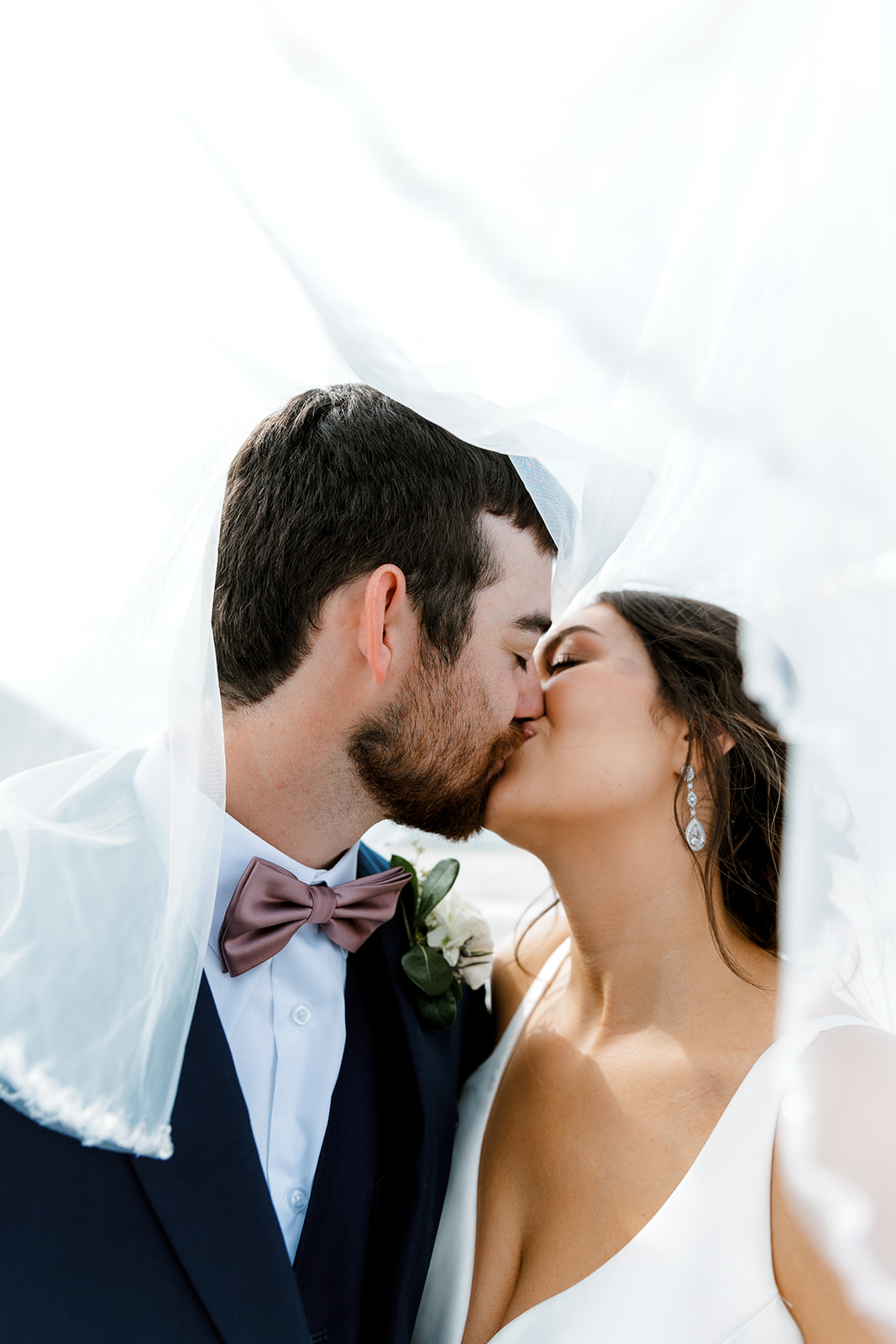 bride and groom kissing under veil with Michigan wedding photographer