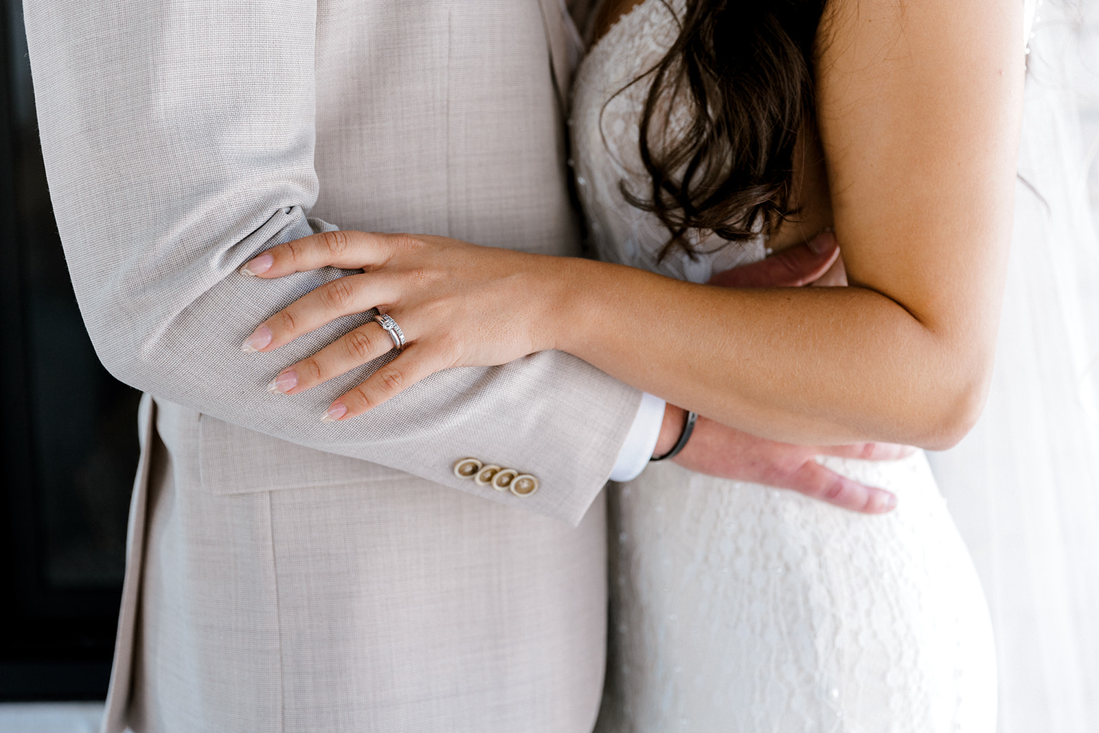 bride and groom holding arms to display their wedding rings