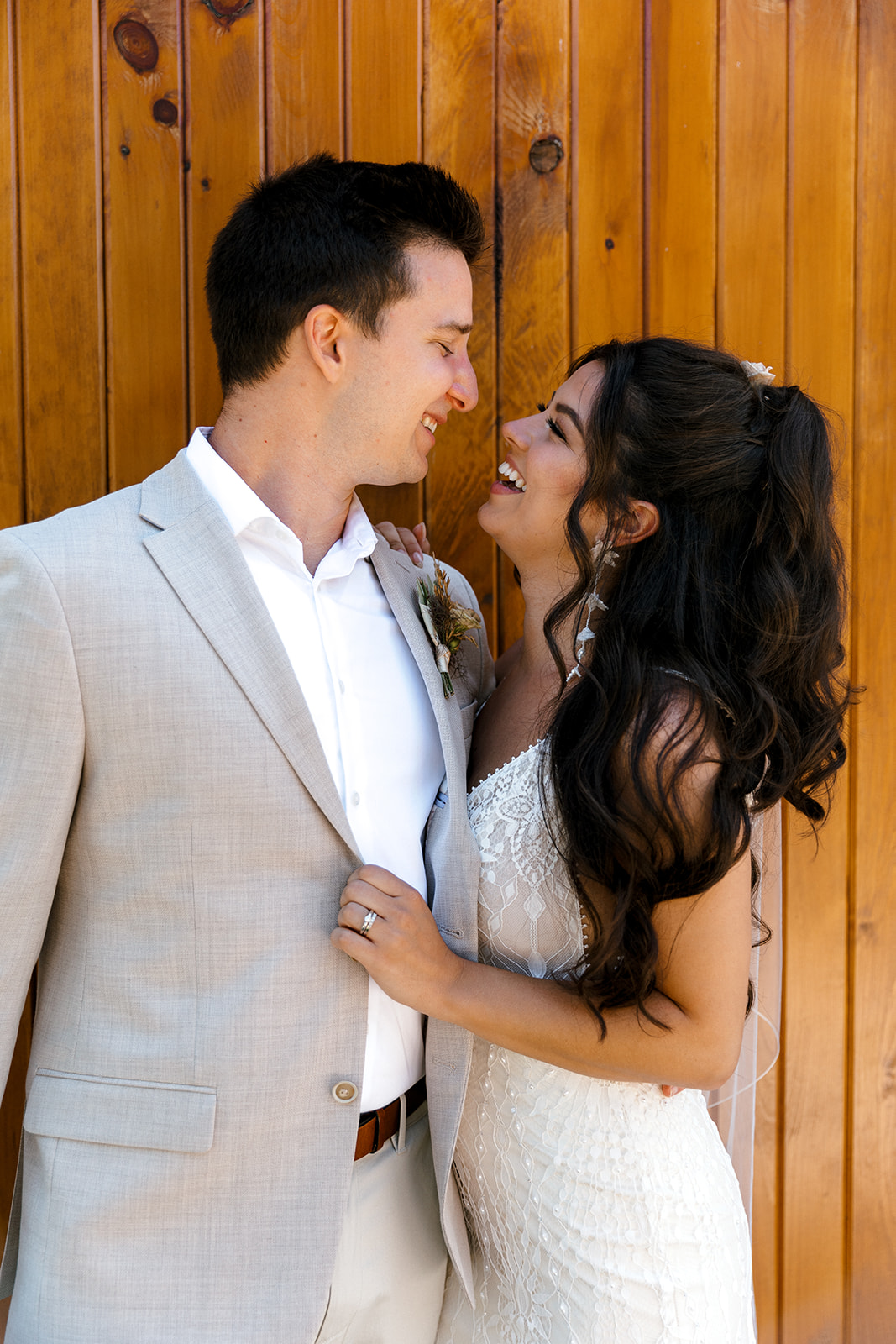 bride and groom photos laughing in front of a wooden door