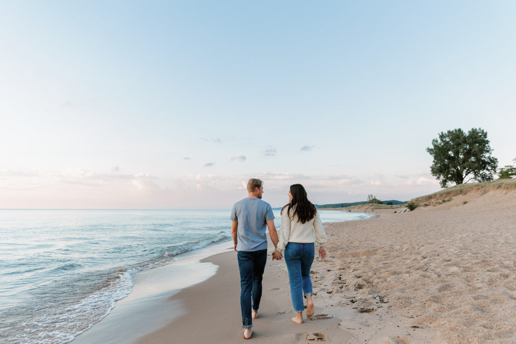 Couple walking along the beach shorline for engagement photos