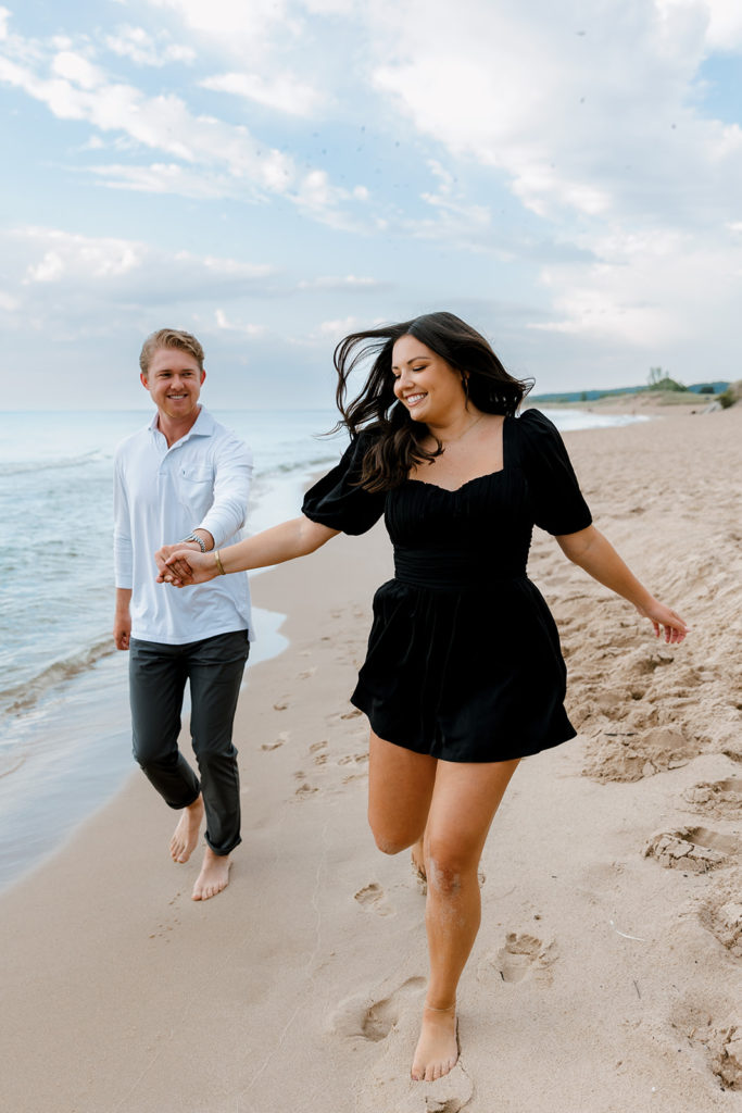 Couple running along the beach during engagement session 