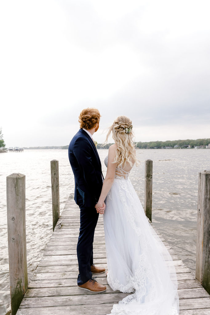 Bride and groom posing in front of lake for wedding portraits