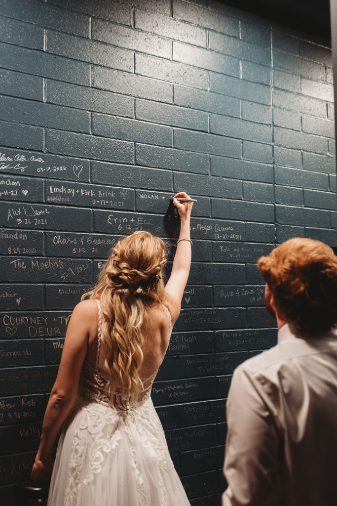 Bride and groom writing their names on wall at Port 393 Holland wedding venue