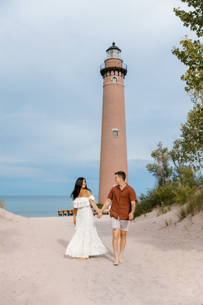 Couple posing in front of little sable point lighthouse in silver lake mi