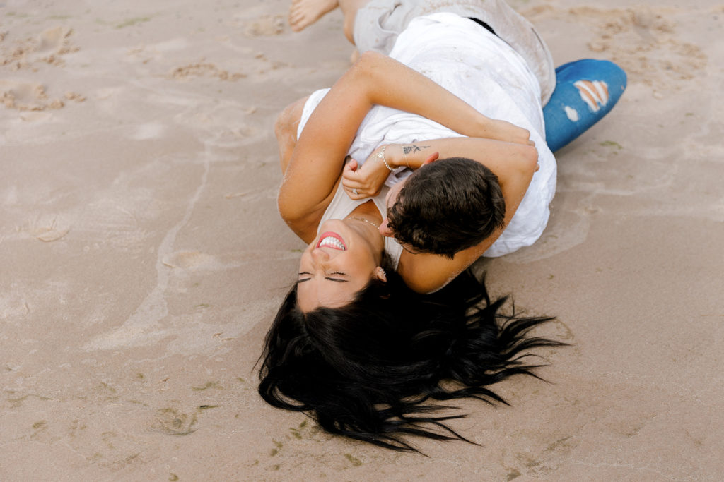 couple rolling around in the sand for photoshoot