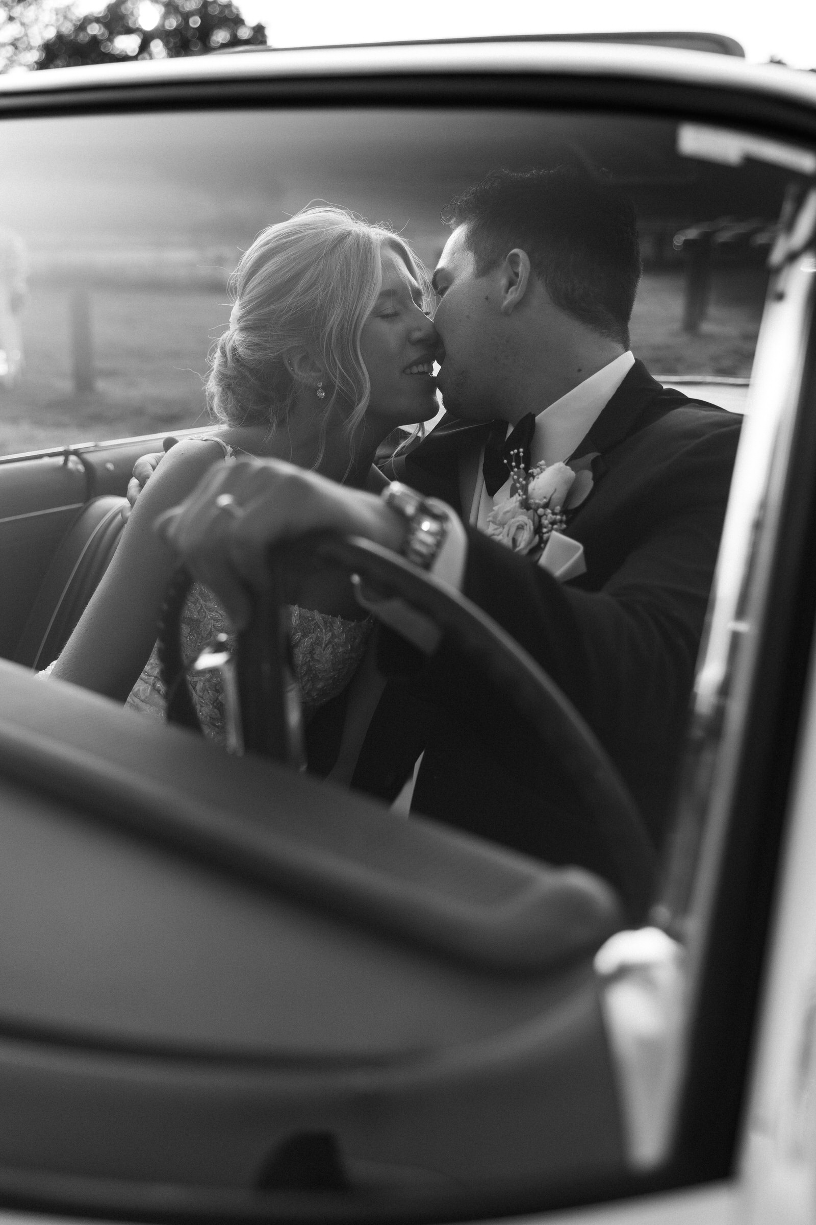 Bride and Groom kissing in a classic old car at the Felt Mansion in Holland Michigan
