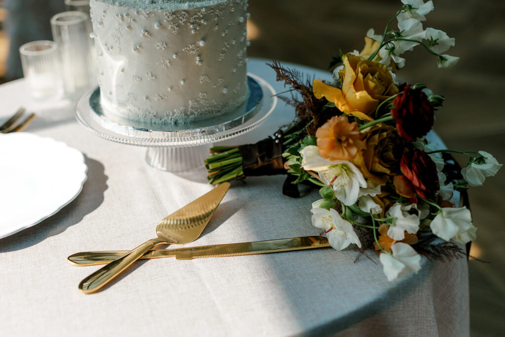 Bridal bouquet and serving ware sit next to luxury wedding cake at mocha-themed wedding