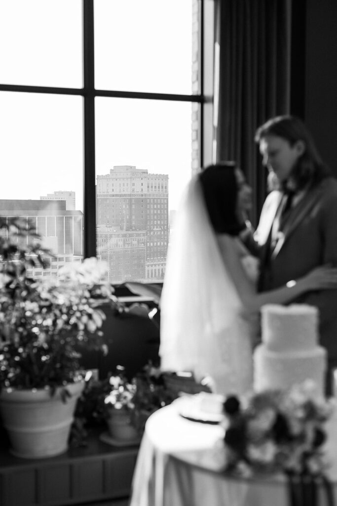 Groom embraces bride while Detroit skyline rises in the distance