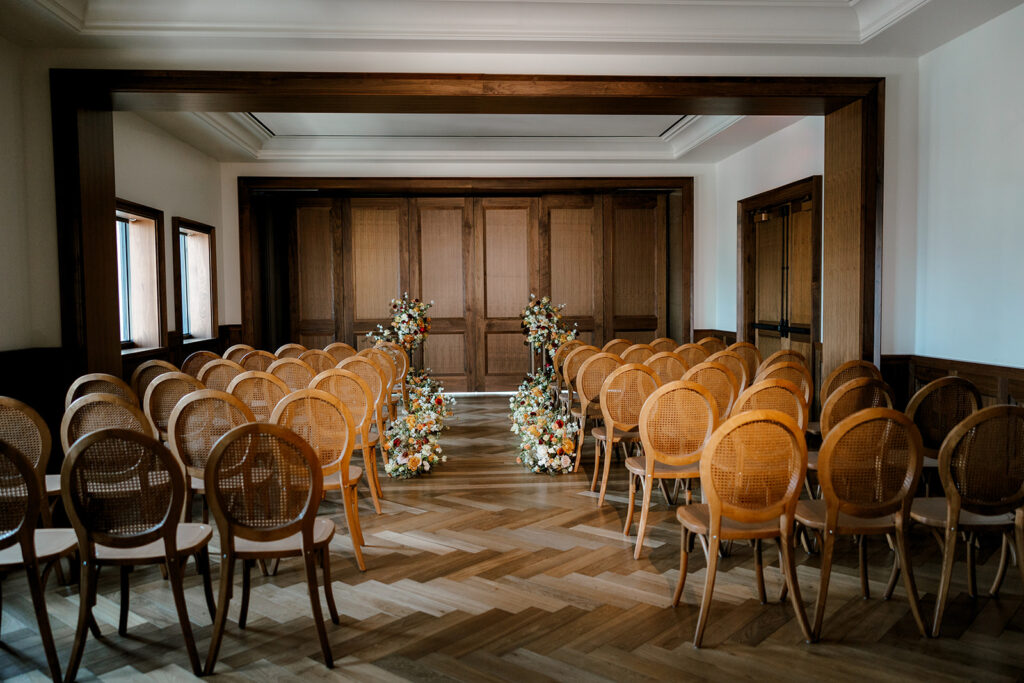 Ceremony space for Book Tower wedding venue in downtown Detroit with cane back chairs and florals lining the aisle.