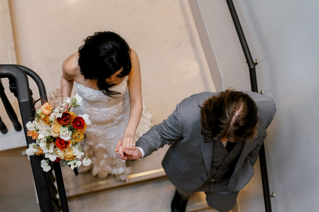 Newlyweds walk hand in hand down stairwell at Detroit wedding