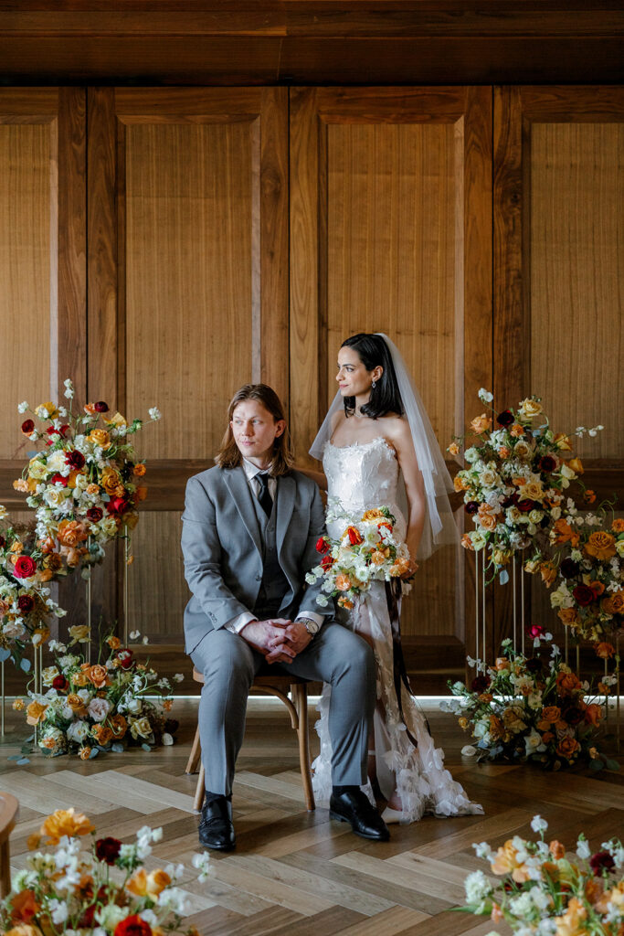 Bride and groom pose for formal portrait surrounded by bold, lush florals