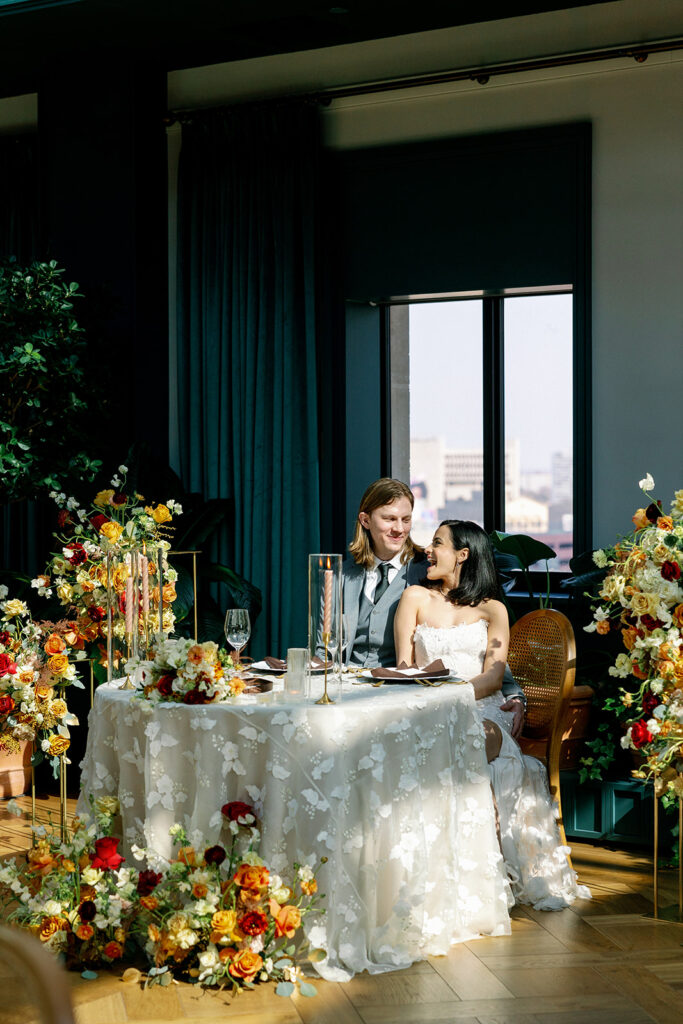 Bride and groom smile at each other at head table of mocha themed wedding in downtown Detroit