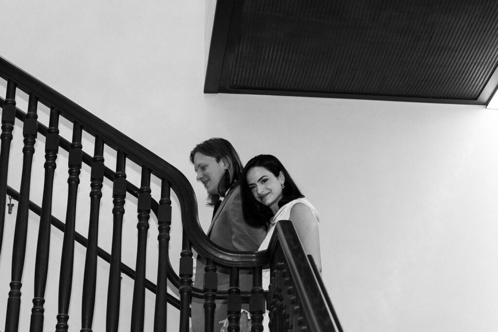 Bride smiles walking up the stairwell hand in hand with her groom