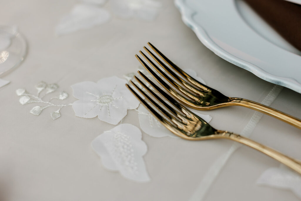 Gold cutlery lays delicately on lace tablecloth