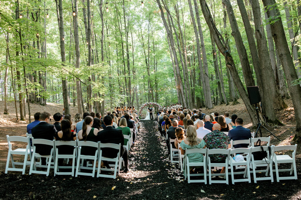 Wide shot of Michigan wedding ceremony tucked in the woods at Bay View at Gallagher Farms
