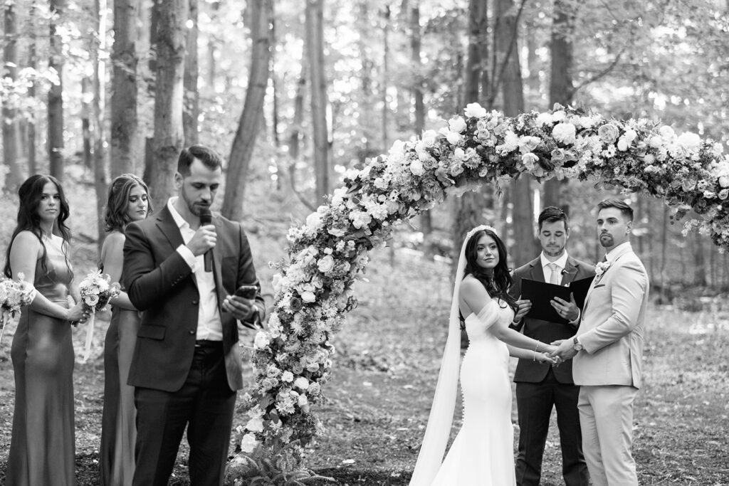 Bride and groom listen intently to family member doing a reading during their Michigan wedding ceremony