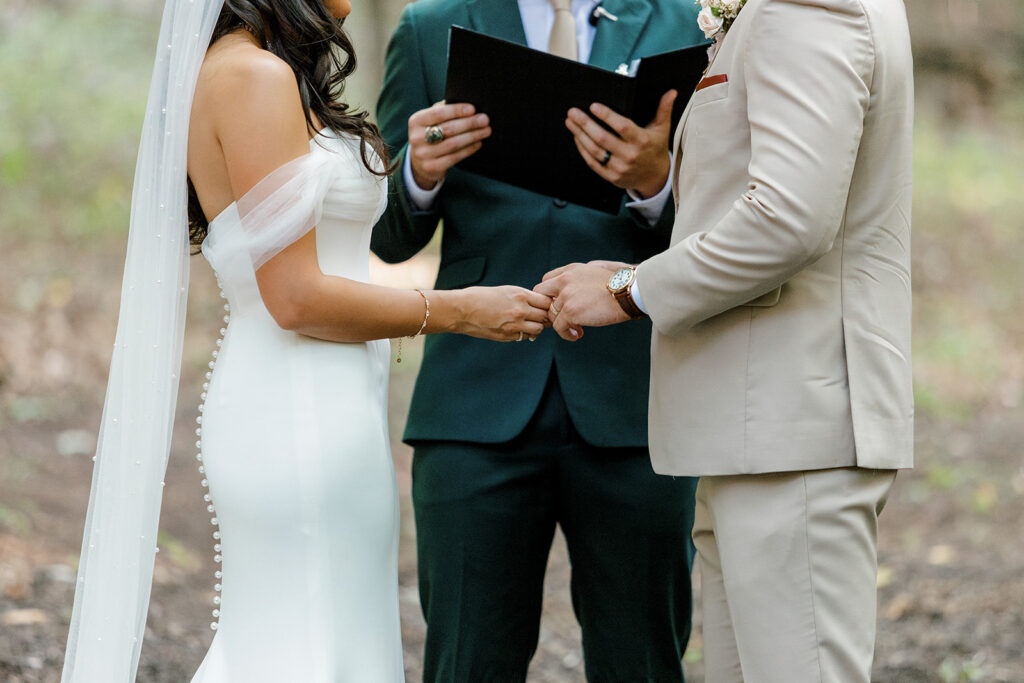 Bride and groom tenderly interlock fingers during ceremony vows