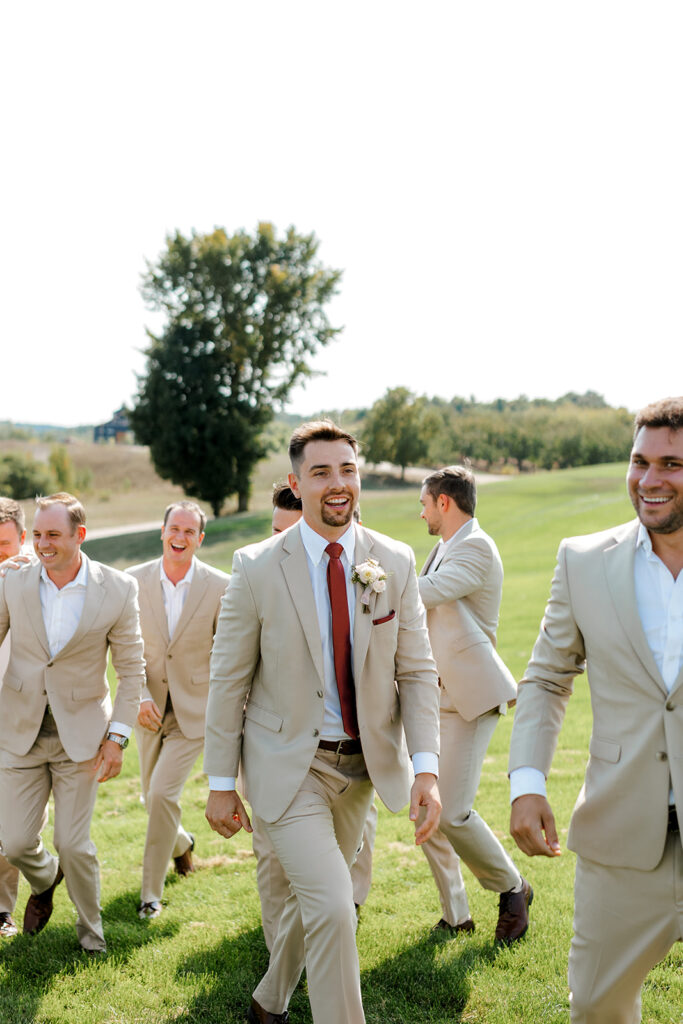 Groom and groomsmen romp across the lawn of Bay View at Gallagher Farms in editorial style candids