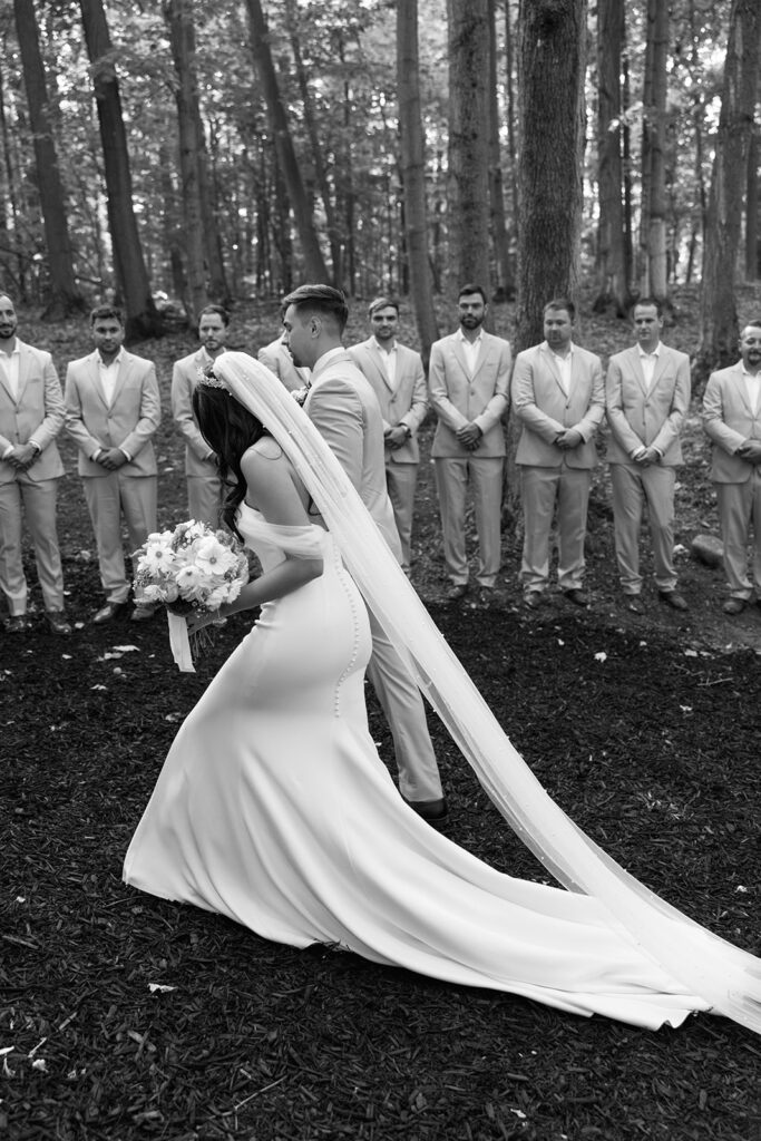 Editorial style candids of bride and groom walking past the entourage of groomsmen.