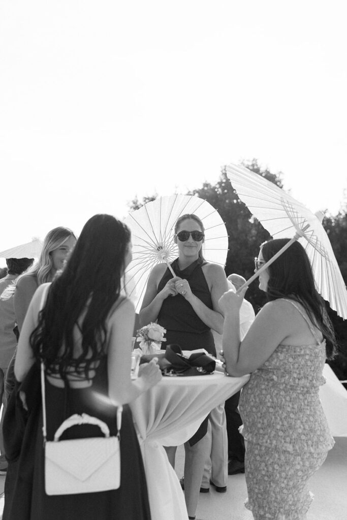 Wedding guests shield their faces from the sun during Michigan wedding cocktail hour