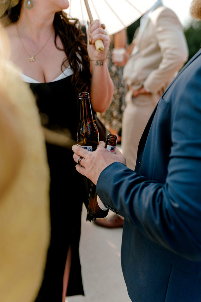 Wedding guests holds multiple beers during cocktail hour