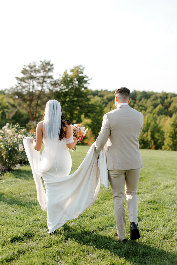 Groom carries bride's train in editorial style candids at Michigan wedding