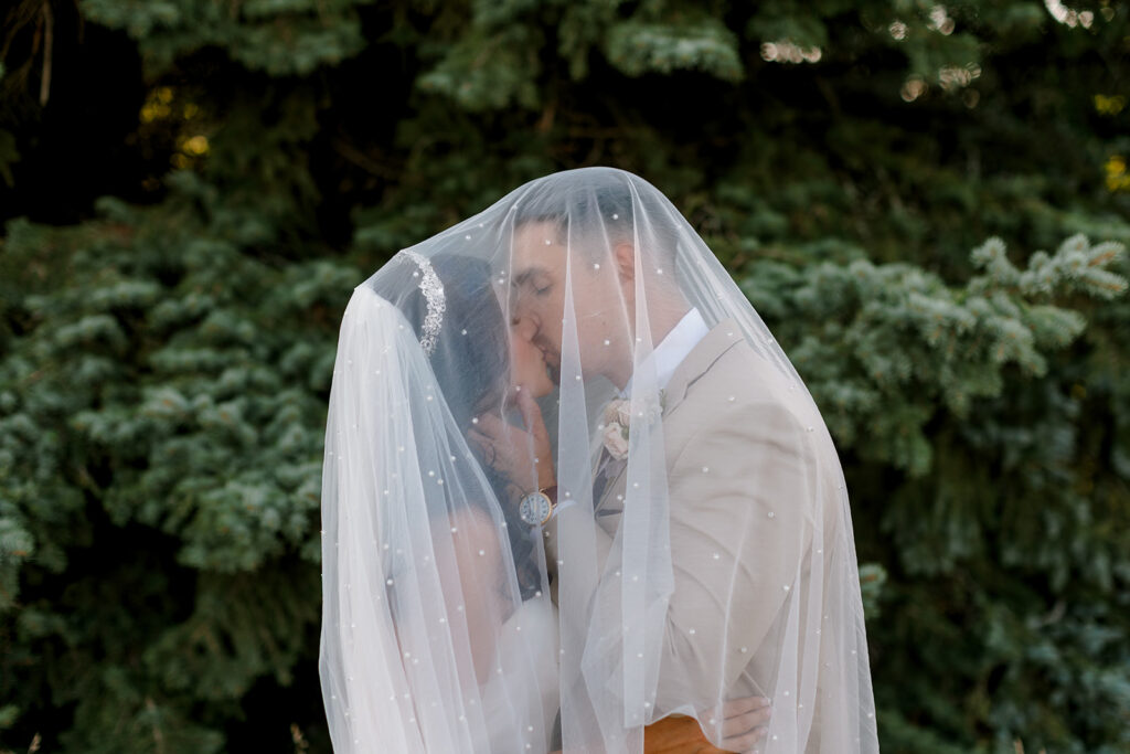 Bride and groom kiss under cover of bride's veil