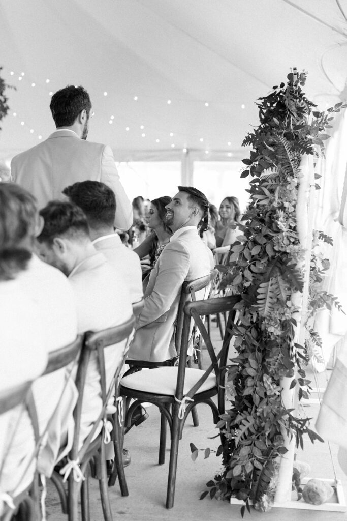Editorial style candids of groom grinning as he listens intently to best man's speech