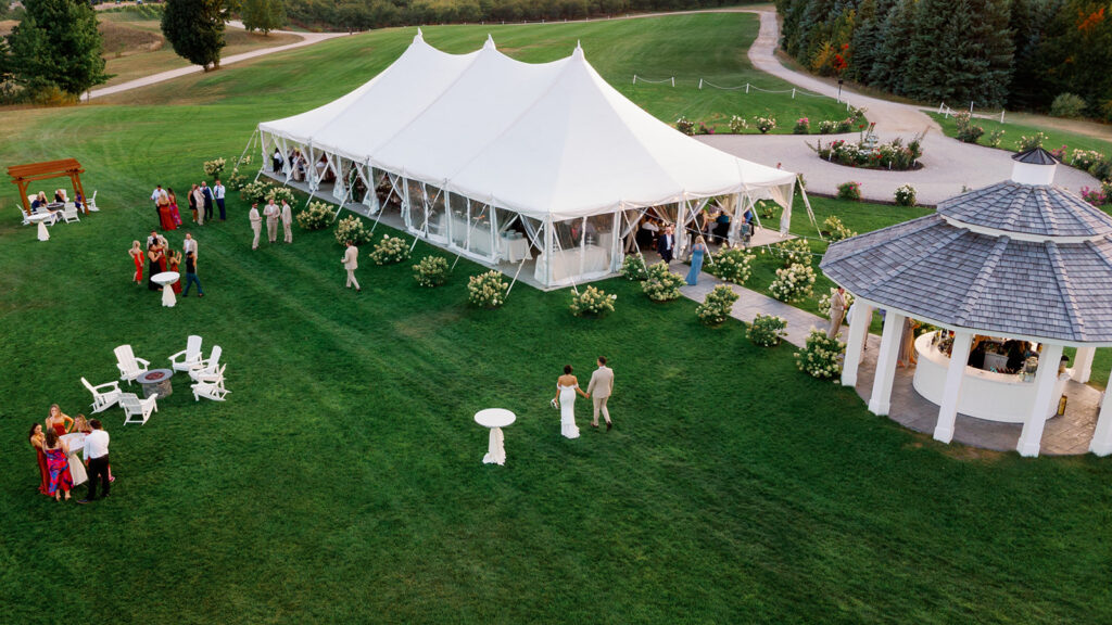 Drone view of bride and groom approaching their reception tent at Bay View at Gallagher Farms in Michigan wedding