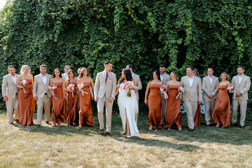 Large wedding party in beige suits and rustic orange dresses at Michigan wedding
