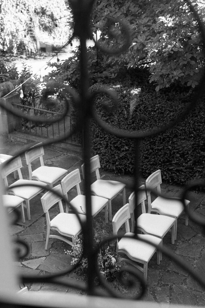 Romantic garden ceremony setup with vintage chairs and floral aisle at European style wedding venue