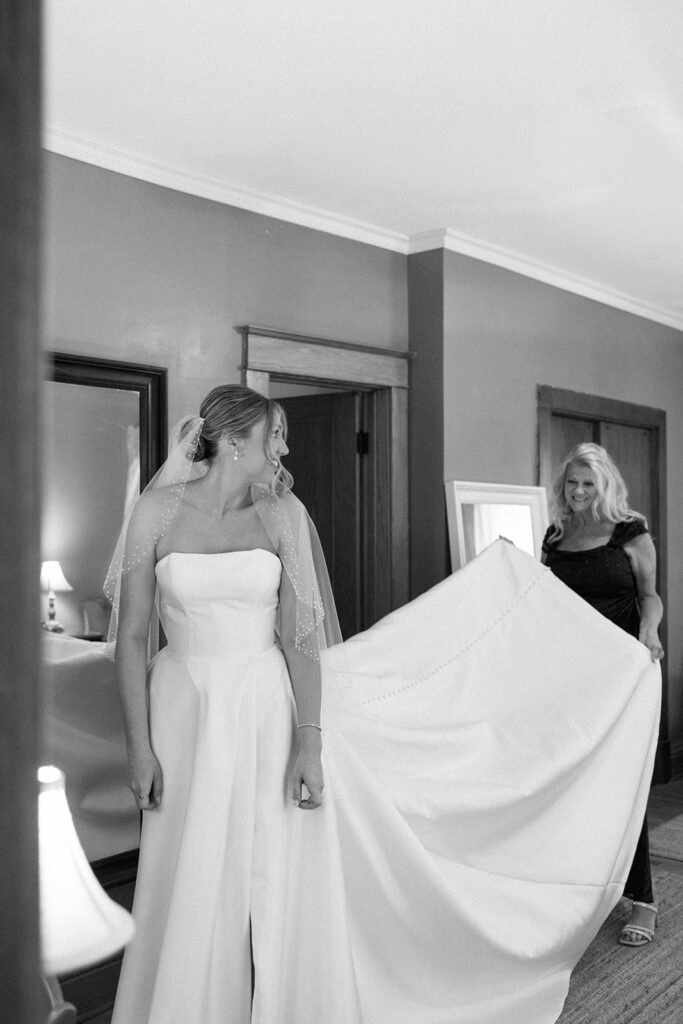 Bride getting ready as bridesmaid adjusts dress, a key moment to include on your wedding shot list.