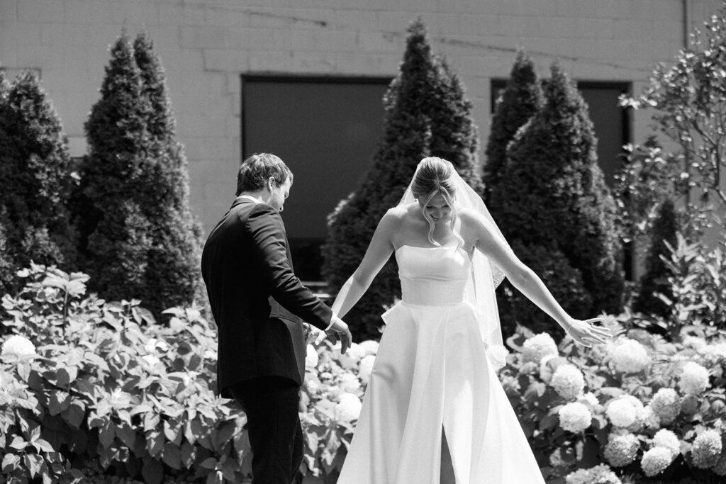 Black and white photo of first look moment, an emotional and unscripted first look wedding photo in a garden setting.