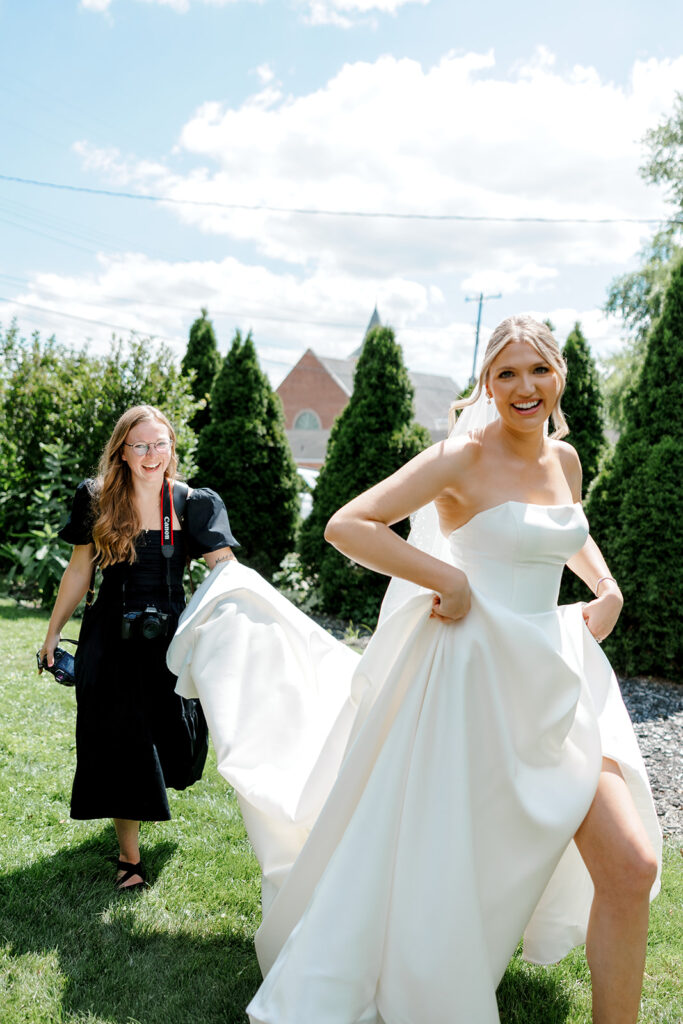 Bride walking with her dress held up by her photographer, capturing candid movement and joyful pre-ceremony energy.