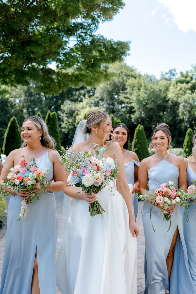 Bride and bridesmaids laughing together, showcasing joyful, unposed bridal party portraits.