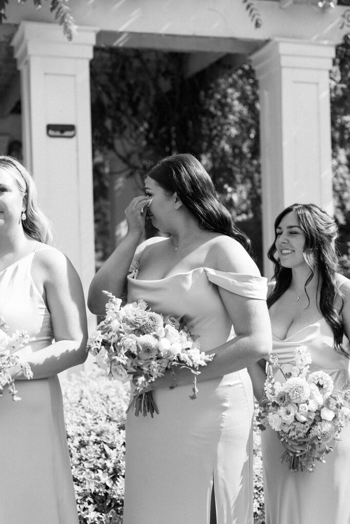 Bridesmaids watching ceremony procession, a candid moment of joy and connection.