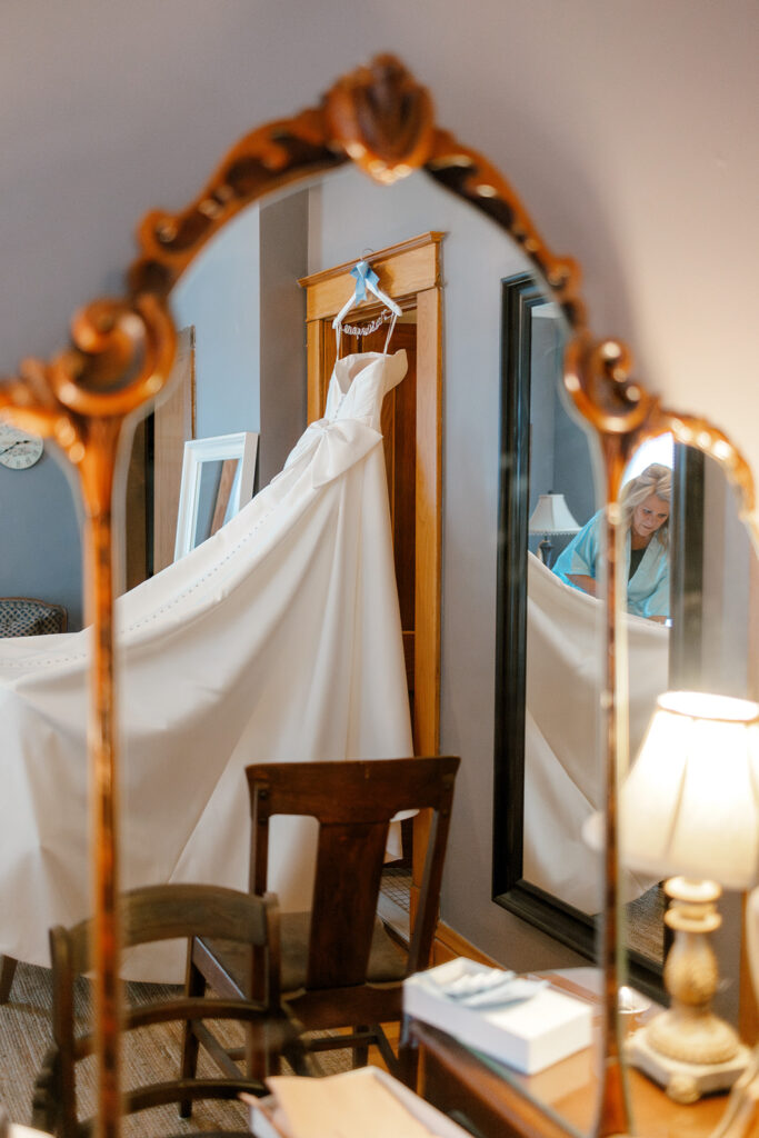 Wedding dress displayed on vintage mirror with layered reflections, a storytelling wedding prep image in a Michigan getting-ready space.