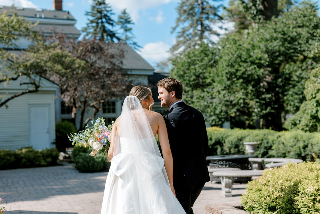 Groom walking hand-in-hand with bride post-ceremony, captured in the garden—a storytelling-style wedding photo.